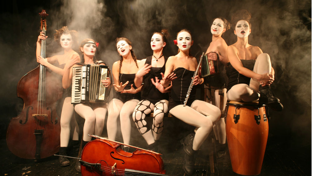 The seven members of Dakh Daughters stand on a smoky stage, wearing white face paint, surrounded by instruments.