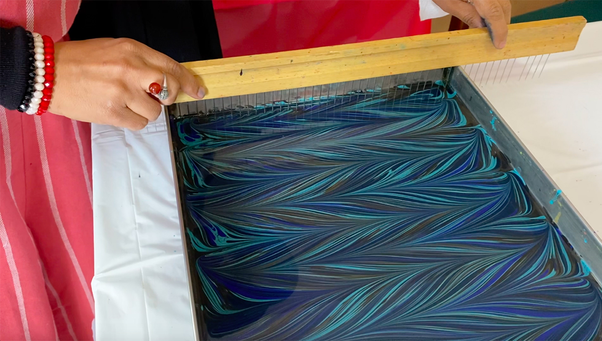 A basin containing paints in shades of blue and green mixed together to make a marbled pattern. 