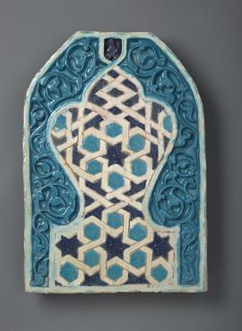 Blue, teal and white panel in the form of a mihrab arch delicately carved in high relief enclosing an inner trefoil palmette standing on a short waisted foot.